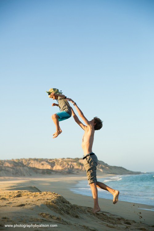 a boy tosses another into the air at a beach