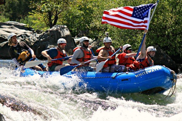 rafters hoist a flag as they hit the rapids